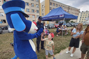 Na zdjęciu widać dzielnicowego oraz maskotkę Śląskiej Policji, która przybija tzw. piątkę z chłopcem