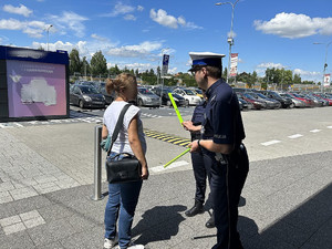 Na zdjęciu widać policjanta przekazującego kobiecie odblaskową opaskę.