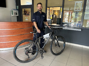 Na zdjęciu widać policjanta przytrzymującego rower. W tle znajduje się stanowisko kierowania żorskiej Policji.