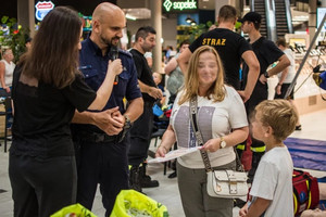 Na zdjęciu widać policjanta oraz kobietę i dziecko podczas zajęć profilaktycznych w żorskiej galerii.