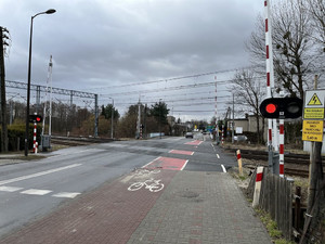 Na zdjęciu widać przejazd kolejowy, którego zapory są podniesione, a sygnalizator świetlny nadaje czerwone światło.