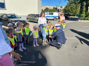 Na zdjęciu widać policjanta rozmawiającego z grupą przedszkolaków.