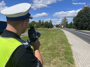 Na zdjęciu widać policjanta trzymającego w rękach miernik prędkości.