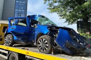 Na zdjęciu widać uszkodzony niebieski samochód umieszczony na lawecie.