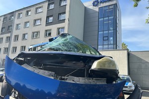 Na zdjęciu widać uszkodzony niebieski samochód umieszczony na lawecie. W tle widać budynek żorskiej Policji.
