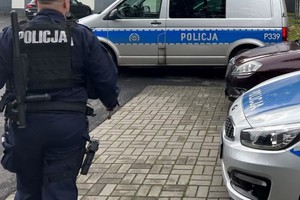 Na zdjęciu widać policjanta oraz radiowozu, w tle widoczne są zabudowania żorskiej Policji.