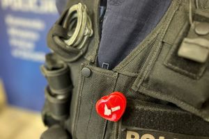 Na zdjęciu widać policjanta ubranego w kamizelkę taktyczną, na kamizelce ma przyczepione odblaskowe serce z logiem Miasta Żory