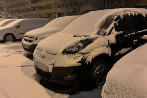 Na zdjęciu widać samochody zaparkowane na parkingu osiedlowym. W tle widać blok mieszkalny. Samochody są mocno ośnieżone.