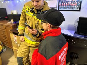 Na zdjęciu widać strażaka, który rozmawia z młodym druhem OSP.