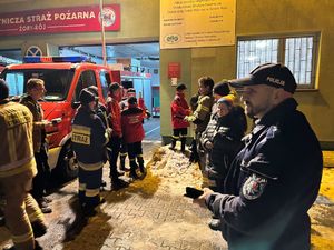 Na zdjęciu widać policjanta, strażaków i uczestników przed budynkiem OSP w Roju.