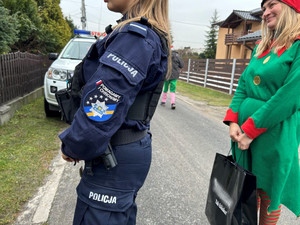 Na zdjęciu widać policjantkę oraz kobietę przebraną za elfa, w tle pojazd straży pożarnej.