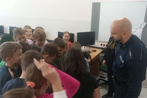 Na zdjęciu widać policjanta oraz uczniów szkoły podstawowej.