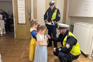 Na zdjęciu widać policjantów oraz dwie dziewczynki. Mundurowi przekazują odblaski.