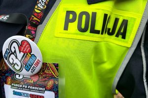 Na zdjęciu widać policjanta, który ma na szyi identyfikator WOŚP na tle odblaskowej, policyjnej kamizelki.