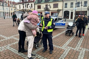 Na zdjęciu widać policjantów i radiowóz na płycie żorskiego Rynku. Policjant rozdaje odblaski.