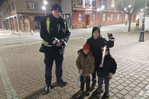 Na zdjęciu widać policjanta oraz dzieci trzymające odblaski w dłoniach.