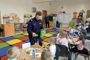 Na zdjęciu widać policjanta rozdającego elementy odblaskowe.