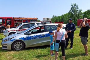 Na zdjęciu widać policjanta, kobietę, mężczyznę oraz dziecko przy radiowozie. Mężczyzna na oczach ma założone alkogogle.