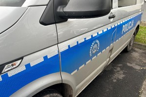 Na zdjęciu widać bok policyjnego radiowozu z emblematem/napisem Policja.