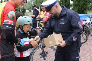 Na zdjęciu widać policjanta przekazującego odblask chłopcu.