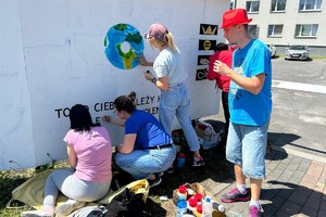 Na zdjęciu widać pracowników i uczestników warsztatów terapii zajęciowej tworzących mural.