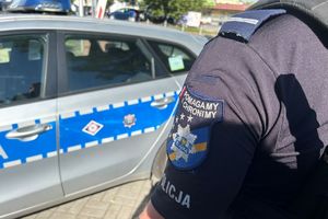 Na zdjęciu widać policjanta, a w tle radiowóz.