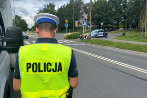 Na zdjęciu widać policjanta ubranego w żółtą kamizelkę na miejscu zdarzenia drogowego.