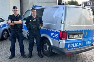 Na zdjęciu widać policjantów na tle policyjnego radiowozu.