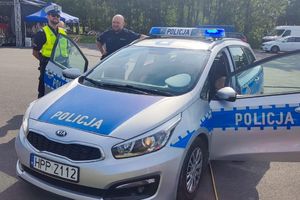 Na zdjęciu widać policjantów ruchu drogowego stojących przed radiowozem.