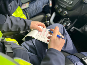 Na zdjęciu widać policjanta wypisującego mandat karny.