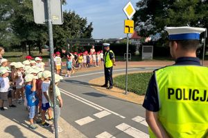 Na zdjęciu widać policjantów, a przed nimi dzieci w szeregu.