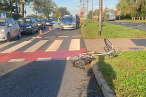 Na zdjęciu widać miejsce zdarzenia drogowego, przejście dla pieszych i przejazd dla rowerzystów. W tle policyjny radiowóz.