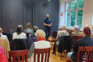 Na zdjęciu widać seniorów i policjanta podczas prelekcji.