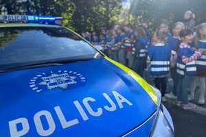 Na zdjęciu widać policyjny radiowóz, policjantów i dzieci.