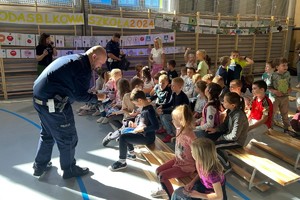 Na zdjęciu widać policjanta rozdającego odblaskowe kamizelki.