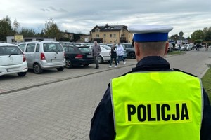 Na zdjęciu widać policjanta, a w tle parking przy cmentarzu.