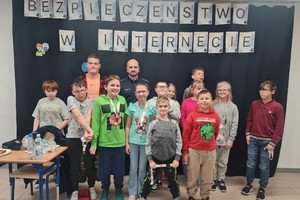 Na zdjęciu widać policjanta oraz uczniów szkoły podstawowej.