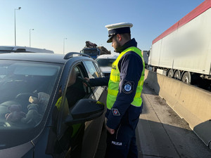 Na zdjęciu widać policjantów podczas akcji badania trzeźwości na węźle autostrady A1. Widać kontrolowane samochody osobowe i ciężarowe.