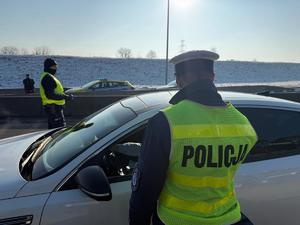 Na zdjęciu widać policjantów podczas akcji badania trzeźwości na węźle autostrady A1. Widać kontrolowane samochody osobowe i ciężarowe.