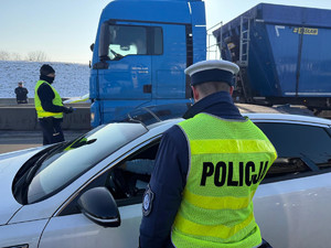 Na zdjęciu widać policjantów podczas akcji badania trzeźwości na węźle autostrady A1. Widać kontrolowane samochody osobowe i ciężarowe.