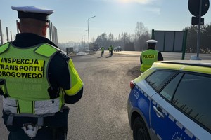 Na zdjęciu widać policjanta, radiowóz oraz inspektora transportu drogowego.