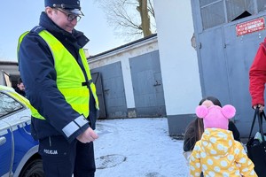 Na zdjęciu widać policjanta, radiowóz i dzieci.