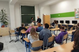 Na zdjęciu widać policjanta i uczestników spotkania.