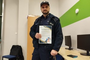 Na zdjęciu widać policjanta trzymającego w dłoniach podziękowanie.