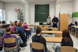 Na zdjęciu widać policjanta i uczestników spotkania.