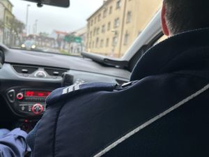 Na zdjęciu widać policjanta siedzącego w radiowozie podczas jazdy.