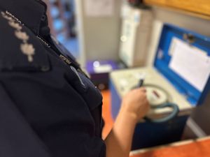 Na zdjęciu widać policjanta obsługującego alkomat.