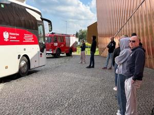 Na zdjęciu widać ambulans krwiodawstwa oraz czekających w kolejce krwiodawców. W tle muzeum ognia oraz stary wóz strażacki.