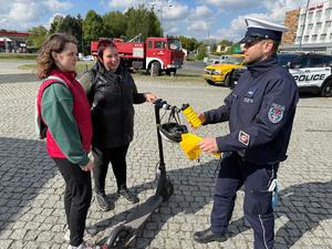 Na zdjęciu widać uczestniczki pikniku rozmawiające z policjantem. Policjant wręcza uczestniczkom materiały promujące akcję &quot;z trzeźwością mi po drodze&quot;.
