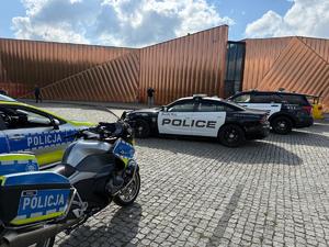 Na zdjęciu widać amerykańskie oraz polskie radiowozy. W tle muzeum ognia.